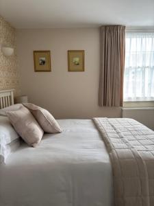 a bedroom with a bed with pillows and a window at Canterbury Guest House in Sidmouth