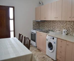a kitchen with a washing machine next to a table at Stone-built house Vrontados Chios 3' from beach in Vrontádos