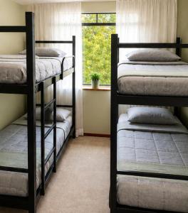 a room with three bunk beds and a window at Bergamota Hostel in Curitiba