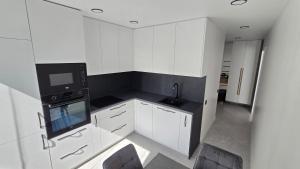 a kitchen with white cabinets and a black microwave at Cozy apartment in Šiauliai
