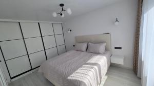 a bedroom with a large bed with white walls at Cozy apartment in Šiauliai
