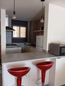 a kitchen with two red stools at a counter at Oasis Mediterráneo in Ifach