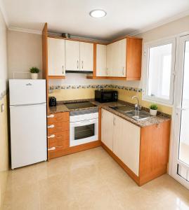 a kitchen with wooden cabinets and a white refrigerator at La Riviera Residence in Rojales