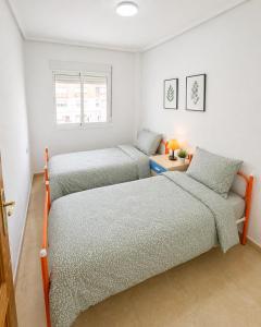 two twin beds in a room with white walls at La Riviera Residence in Rojales
