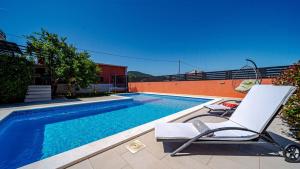 a swimming pool with a chair next to a swimming pool at Villa Anna by Villas Guide in Vela Luka