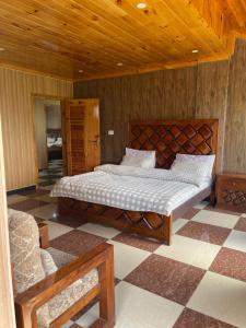 a bedroom with a large bed and a chair at Hillside Cottages, Kala Bagh in Nathia Gali