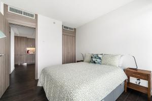 a bedroom with a bed and a white wall at Bright & Cozy 1BR Steps to Brentwood mall in Burnaby