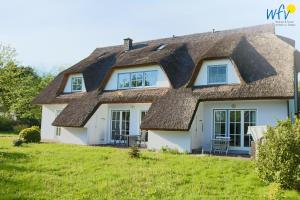 a thatched roof house with a lawn at Haus Wreechen Ferienwohnung Michaelis in Putbus