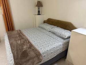 a bed in a small room with a lamp at Glynver Apartments in Christ Church
