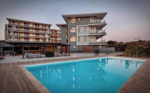 a building with a swimming pool in front of a building at Luxury Coastal Escape Coral Point Sibaya Pool & WiFi in Durban