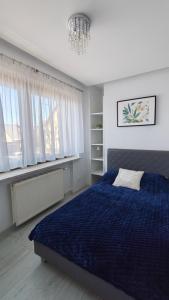 a bedroom with a blue bed and a chandelier at Szafir Kuźnica - Apartamenty 4 min od plaży in Kuźnica