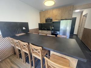 a kitchen with a large black table and chairs at Duplex T4 residence les Etoiles du Sud in Le Lioran
