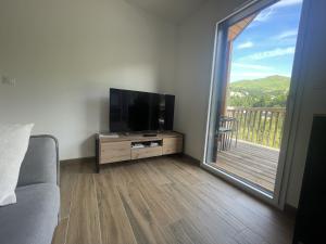 a living room with a flat screen tv and a balcony at Duplex T4 residence les Etoiles du Sud in Le Lioran