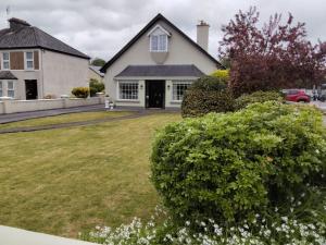 a white house with a yard with bushes at Greenmount Accommodation in Killarney