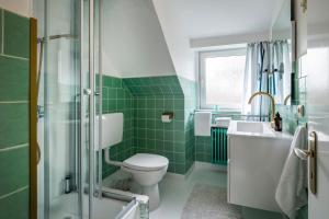 a green bathroom with a toilet and a sink at Ferienhaus Inge in Büsum +16 photos
