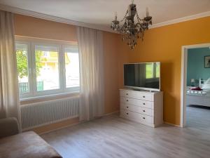 a living room with a television on a dresser and a chandelier at Haus 4 you in Winden am See