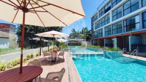 a swimming pool with a table and an umbrella next to a building at Acqua Beach Residence by CTA in Tamandaré