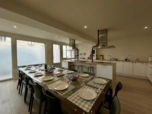 a dining room with a table with chairs and a kitchen at L'Apparth, maison partagée 7 chambres in Parthenay