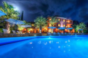 a hotel with a swimming pool at night at The Palm Garden in Ermones