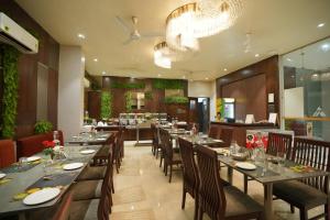 a restaurant with long tables and chairs and a chandelier at Alaukik Hotel in Shirdi