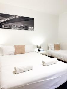 two beds in a room with a picture on the wall at studio Ex hotel room city 107 in Adelaide