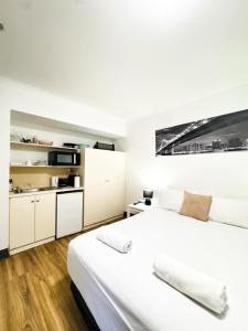 a white bedroom with two beds and a kitchen at studio Ex hotel room city 107 in Adelaide
