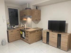 a kitchen with wooden cabinets and a flat screen tv at U Tonyho - Apartmán v centru Strakonice 2-kk in Strakonice