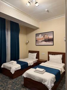 two beds in a hotel room with blue curtains at Almaz Hotel Uzbekistan in Tashkent +28 photos