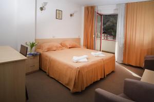a bedroom with a bed with two towels on it at Hotel Vacanța in Geoagiu Băi