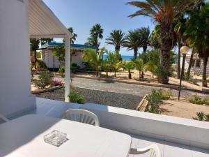 a white table and chairs on a balcony with palm trees at Vilas Praia de Chaves Deluxe house sol y mar in Rabil