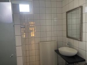 a white tiled bathroom with a sink and a mirror at Haus 4 you in Winden am See +12 photos