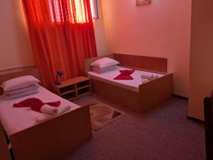 two beds in a small room with red curtains at Hotel Tiver in Câmpia Turzii