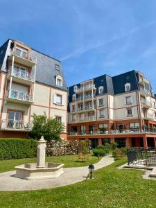 two large apartment buildings with a fountain in the grass at Villa Médicis Trouville-sur-mer in Trouville-sur-Mer