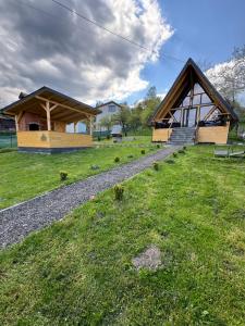 a house with a thatched roof on a green field at Cabana Bucegi View A-Frame Bran in Predeluţ
