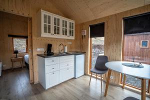 a kitchen with white cabinets and a table in a cabin at Paradise Cottages in Vík