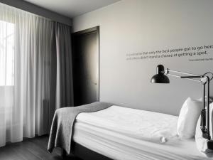 ein Schlafzimmer mit einem Bett, einer Lampe und einem Fenster in der Unterkunft Skuggi Hotel by Keahotels in Reykjavík + 34 Fotos