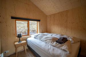 a bed in a wooden room with a window at Paradise Cottages in Vík