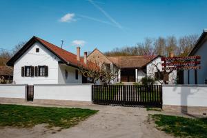 a white house with a fence and a sign at Villány Outback in Kisjakabfalva