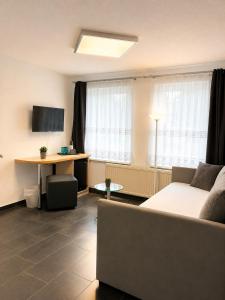 a living room with a couch and a desk and window at Hotel Pension Vineta Rügen in Baabe
