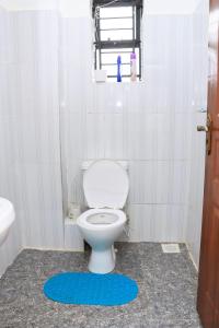 a bathroom with a white toilet and a blue rug at Karani Suites in Nyahururu +5 photos