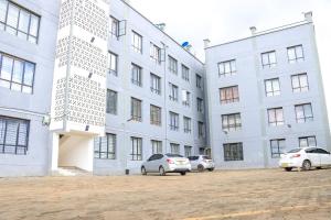 two cars parked in front of a large building at Karani Suites in Nyahururu