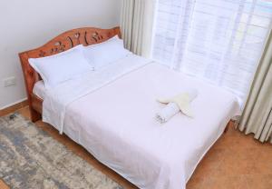 a bedroom with a white bed with a roll on it at Karani Suites in Nyahururu