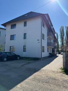 a white building with a car parked next to it at Bounty Home in Bistriţa +8 photos