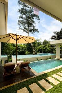 an umbrella and two chairs next to a swimming pool at 3BR Nava villa Ubud in Ubud