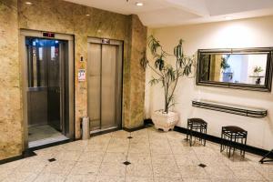 a lobby with two chairs and a mirror on the wall at Hotel Vila Rica Flat in Resende