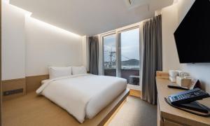 a hotel room with a bed and a window at Bluefrog Hotel in Incheon