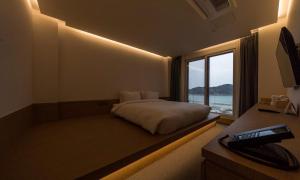 a bedroom with a bed with a window and a desk at Bluefrog Hotel in Incheon