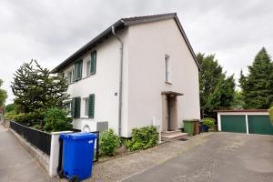 a white house with a blue trash can in front of it at Ferienwohnung Mand in Weinheim