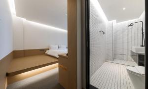 a bathroom with a shower and a toilet and a bed at Bluefrog Hotel in Incheon