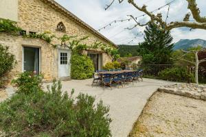 a stone house with a table and chairs on a patio at Gîte la Pigne in Aurel
